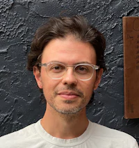 a man wearing glasses is standing in front of a wall