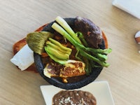 a bowl of food on a table next to a bowl of soup