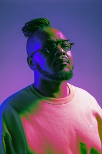 a man with dreadlocks standing in front of a colorful background