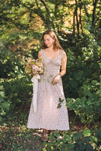 a woman in a floral dress walking through the woods