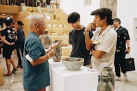 a group of people looking at vases in an art gallery