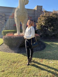 a woman standing in front of a horse statue