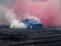 a blue car with pink smoke coming out of it