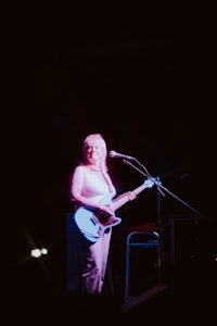 a woman playing a guitar in front of a microphone