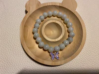 a bracelet with a butterfly charm on a wooden tray