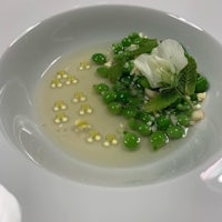 a white bowl with green peas and white flowers