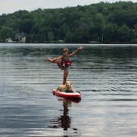 a woman on a stand up paddle board with a dog