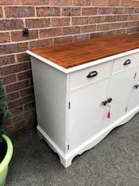 a white sideboard in front of a brick wall