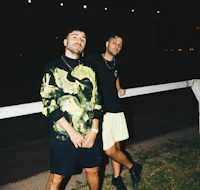 two men standing next to a fence