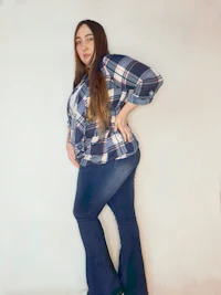 a woman wearing a plaid shirt and flared jeans