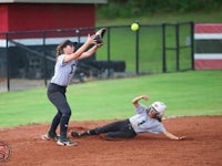a softball player tries to catch a ball during a game