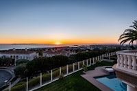 a house with a pool and a view of the ocean at sunset
