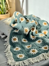 a crocheted blanket with daisies on it