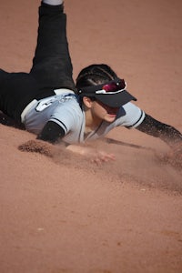 a softball player sliding into base during a game
