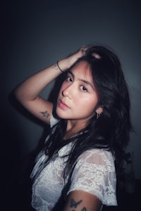a woman with tattoos posing in a dark room
