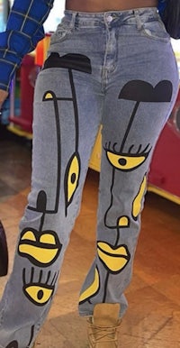 a woman wearing a pair of jeans with a face painted on them