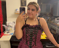 a woman in a pink and black corset taking a selfie