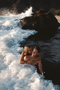a couple embracing in the water on a beach in hawaii