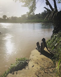 a person sitting on the edge of a river