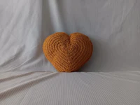 a heart shaped crocheted pillow on a bed