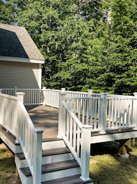 a deck with a white railing and steps