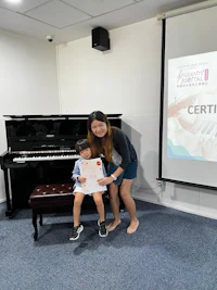 a woman and a child posing for a photo in front of a piano