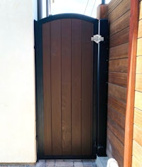 a brown wooden gate with a black handle