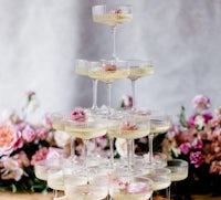 a tower of champagne glasses with pink flowers on top