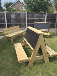 a wooden picnic table and benches in a backyard