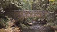 a stone bridge over a stream in the woods