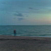 a person walking on the beach at sunset