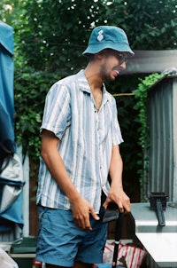 a man in a blue striped shirt standing next to a grill