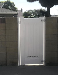 a white gate with a brick wall behind it