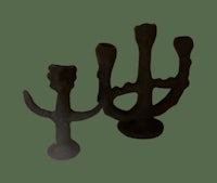 two black candle holders on a green background
