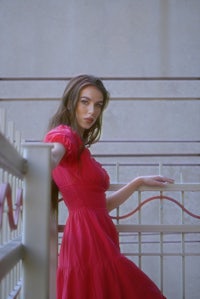 a woman in a red dress posing on a railing