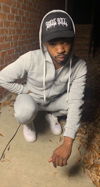 a man crouching down in front of a brick wall