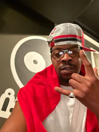 a man wearing glasses and a red cap is making a hand gesture