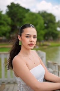 a young woman in a white dress posing by a lake