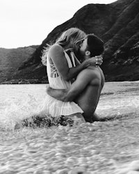 a man and woman kissing in the ocean