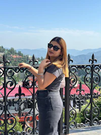 a woman standing on a balcony with mountains in the background