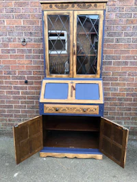 a blue and white antique bureau with a glass door