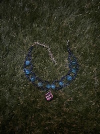 a blue necklace laying on the grass