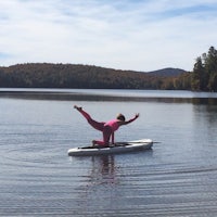 a woman doing yoga on a paddle board in a lake