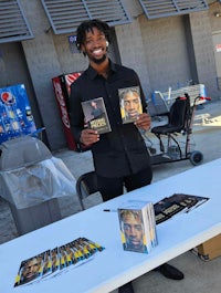 a man holding a book in front of a table