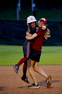 two softball players hugging on the field