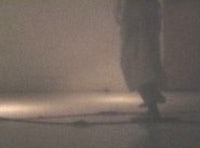 a woman in a white dress standing in a dark room