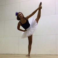 a young girl in a tutu doing a ballet pose