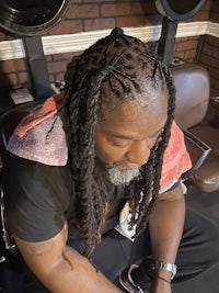 a man with dreadlocks sitting in a chair