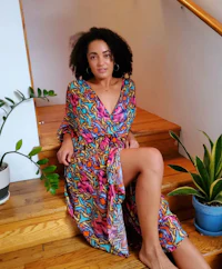 a woman wearing a colorful kaftan sitting on the stairs