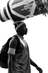 a man carrying a drum on his head